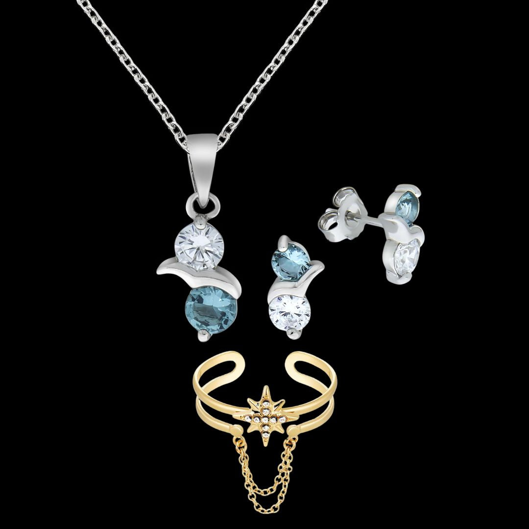 Vor schwarzem Hintergrund ist ein Schmuckset abgebildet. Oben hängt eine silberne Halskette mit einem runden, klaren und einem blauen Stein, darunter ein Paar passende silberne Ohrstecker mit denselben Steinen. Unter dem Set ist ein goldener, offener Fingerring mit Sternmotiv und feinen, hängenden Kettchen zu sehen.